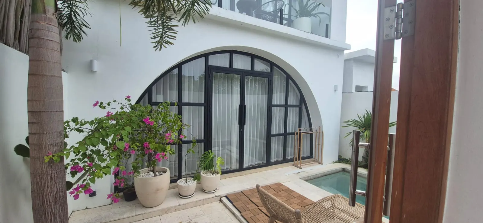 White two-storey villa with arched black-framed glass doors, Batu Bolong Canggu