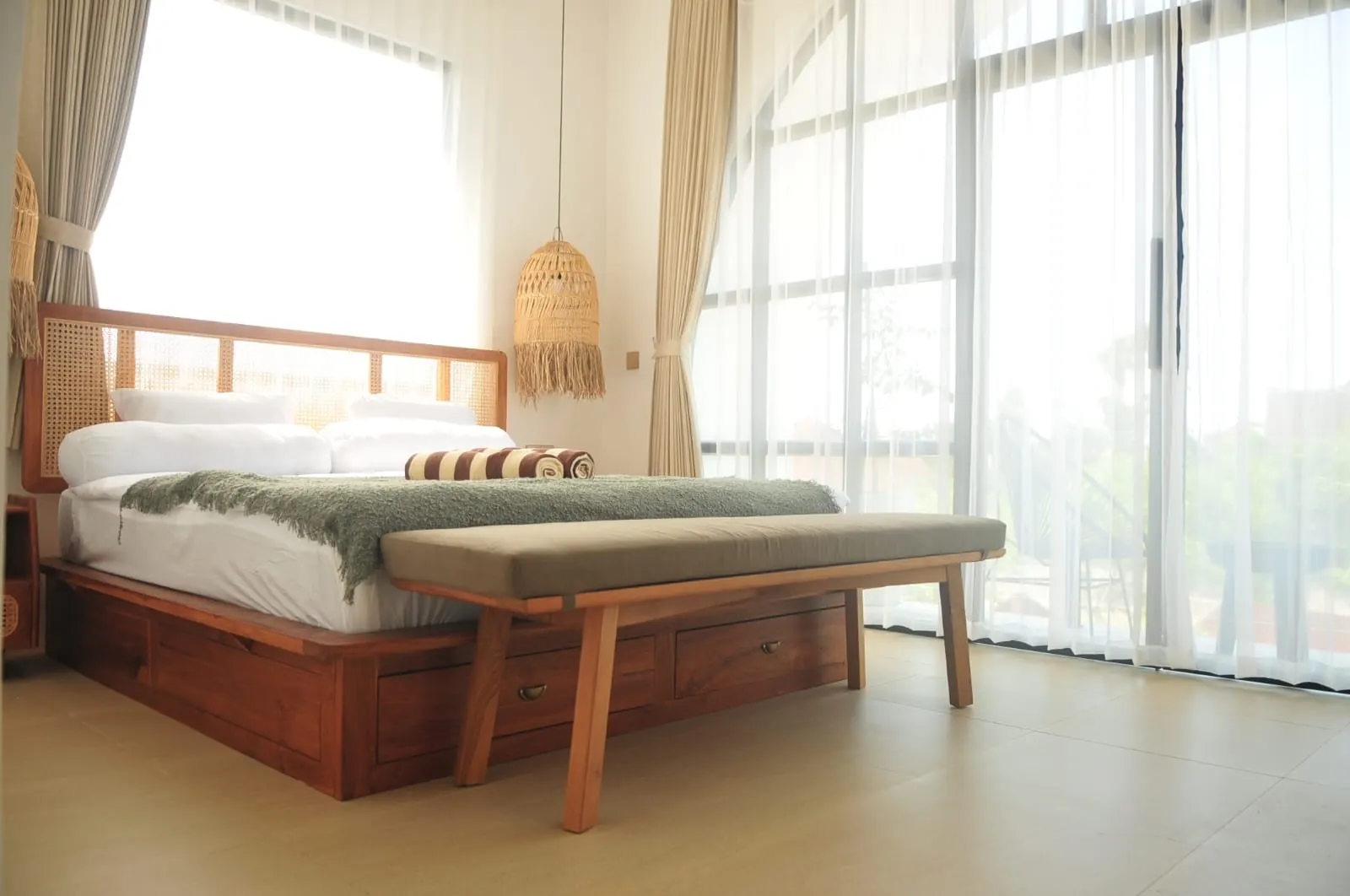 Spacious bedroom with rattan headboard and floor-to-ceiling glass to the balcony