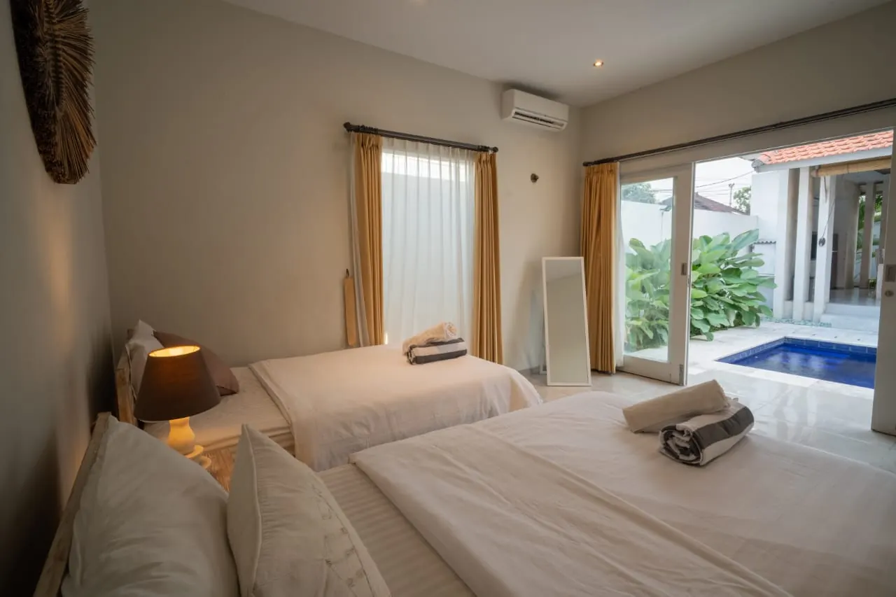 Twin bedroom with glass doors to the pool and garden
